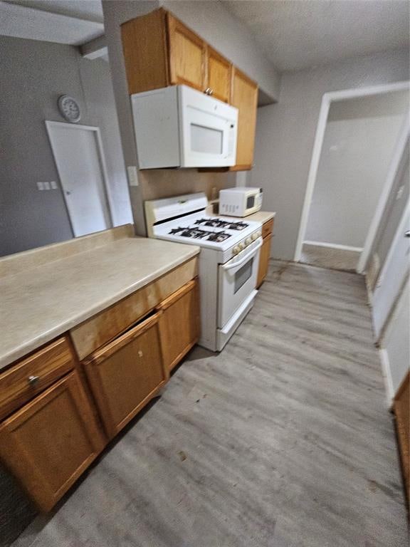 kitchen with light wood-type flooring and white appliances