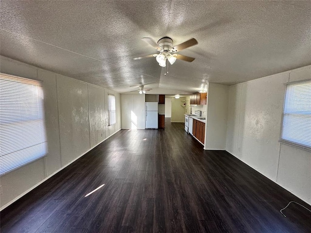 unfurnished living room featuring a textured ceiling, vaulted ceiling, ceiling fan, and dark wood-type flooring