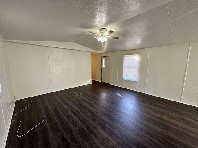 empty room featuring a textured ceiling, lofted ceiling, ceiling fan, and dark hardwood / wood-style floors