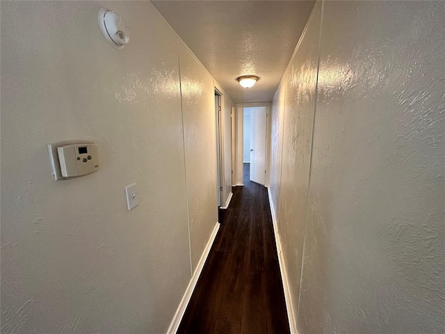 corridor with dark wood-type flooring and a textured ceiling