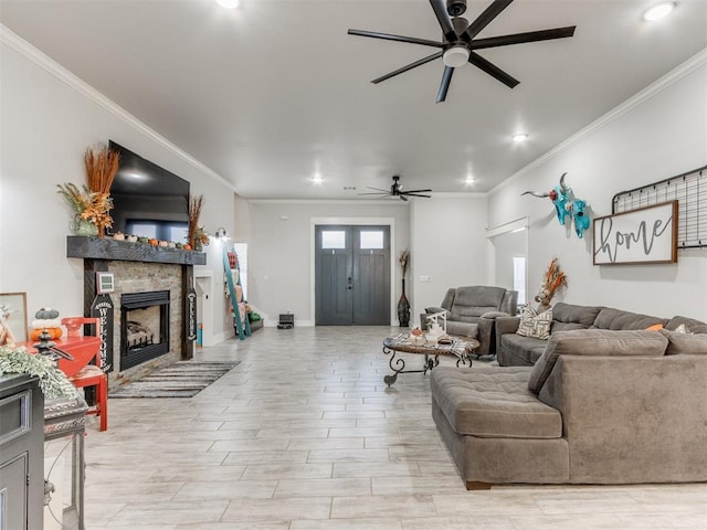 living room with a stone fireplace, ceiling fan, and ornamental molding