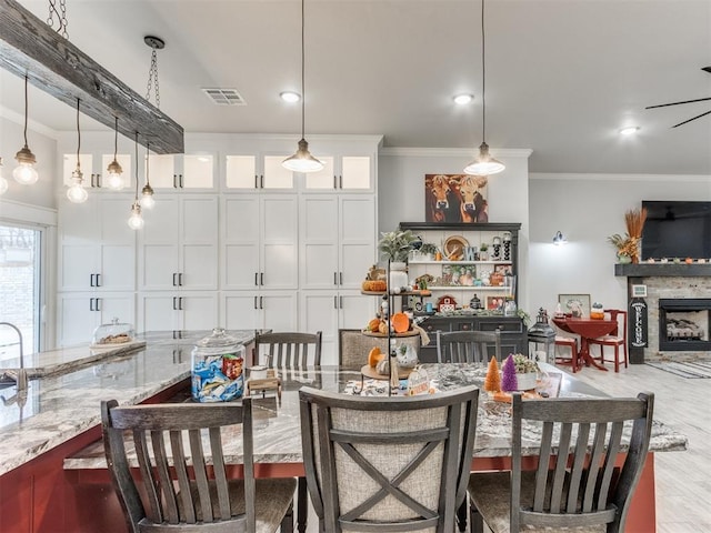 dining space featuring a stone fireplace and crown molding