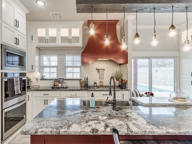 kitchen with backsplash, dark stone countertops, white cabinetry, and hanging light fixtures