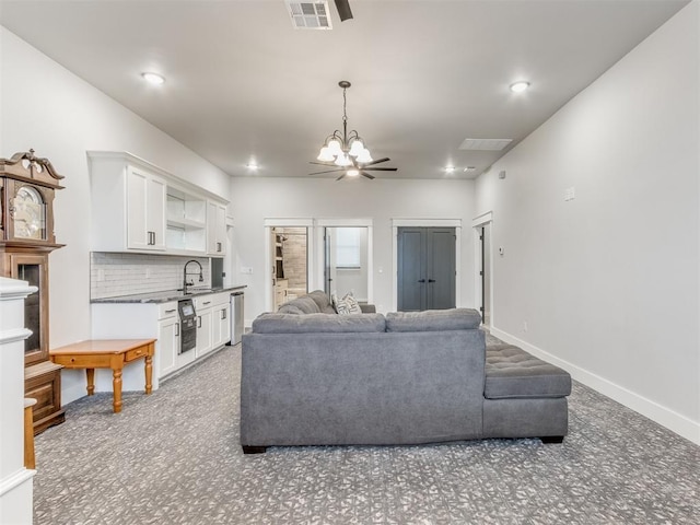 living room featuring carpet flooring, ceiling fan with notable chandelier, sink, and beverage cooler