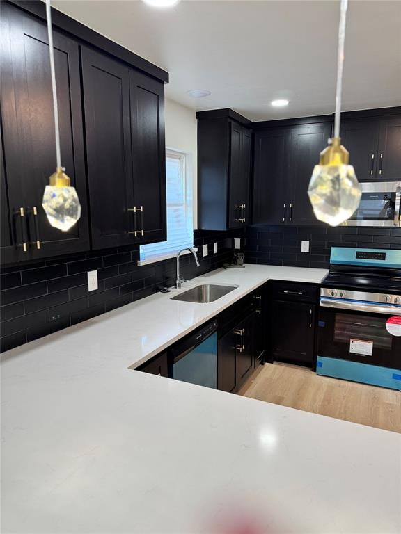 kitchen featuring decorative backsplash, sink, hanging light fixtures, and stainless steel appliances