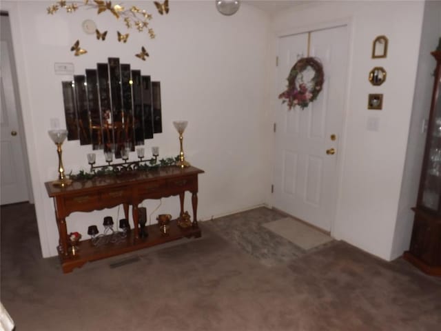 foyer entrance featuring dark colored carpet