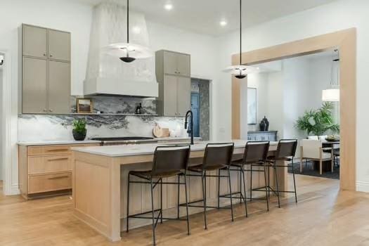 kitchen featuring a breakfast bar area, an island with sink, and hanging light fixtures