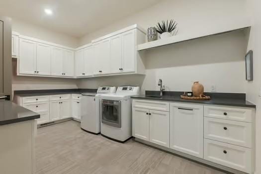 laundry room featuring sink, light hardwood / wood-style flooring, cabinets, and washing machine and clothes dryer