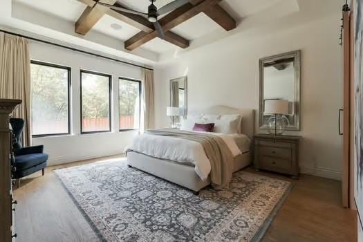 bedroom featuring ceiling fan, coffered ceiling, hardwood / wood-style floors, and beam ceiling