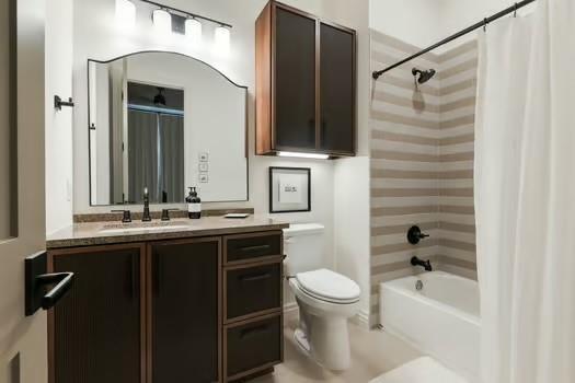 full bathroom featuring toilet, vanity, and shower / bathtub combination with curtain