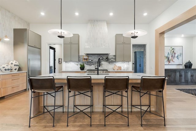 kitchen with gray cabinetry, custom range hood, a breakfast bar, and a spacious island