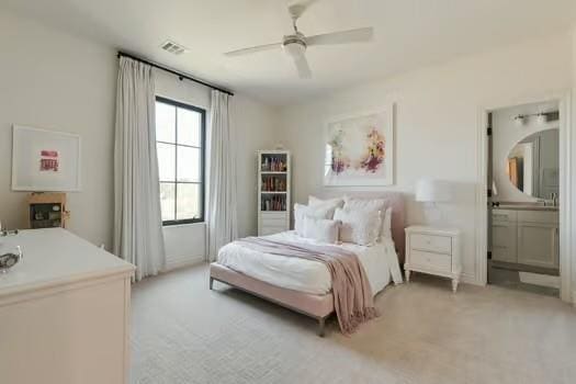 carpeted bedroom with ensuite bathroom and ceiling fan