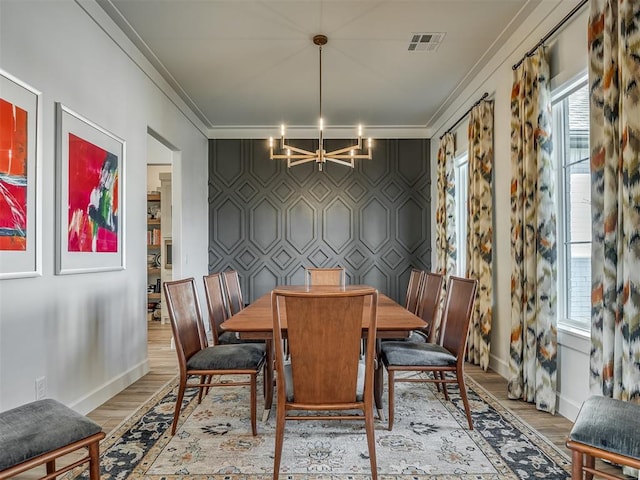 dining area featuring ornamental molding, hardwood / wood-style flooring, and a notable chandelier