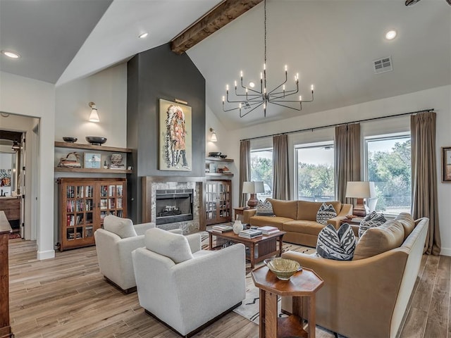 living room with beamed ceiling, a fireplace, a wealth of natural light, and light hardwood / wood-style flooring