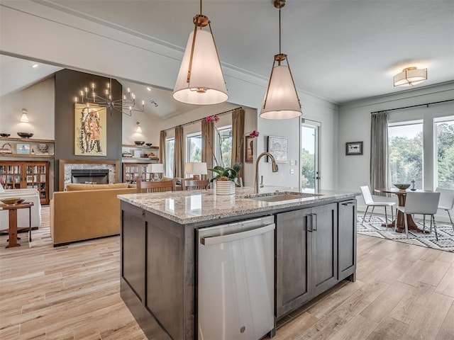 kitchen with light stone countertops, sink, pendant lighting, dishwasher, and lofted ceiling