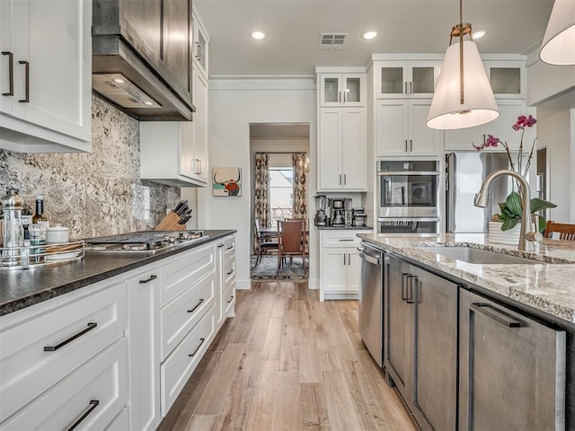 kitchen with appliances with stainless steel finishes, dark stone counters, sink, decorative light fixtures, and white cabinetry