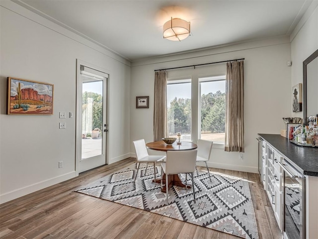 dining space with plenty of natural light, light hardwood / wood-style floors, ornamental molding, and wine cooler