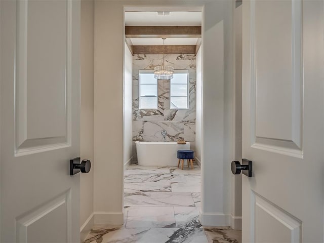 bathroom featuring a washtub and an inviting chandelier