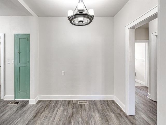 spare room featuring a chandelier and hardwood / wood-style flooring