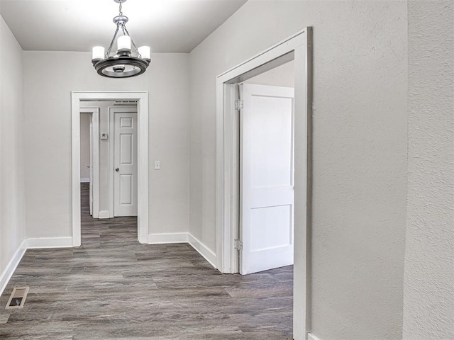 hall featuring dark hardwood / wood-style floors and a notable chandelier