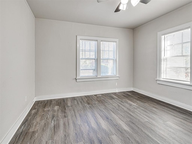 empty room featuring a healthy amount of sunlight, dark hardwood / wood-style flooring, and crown molding