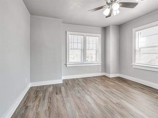 empty room with hardwood / wood-style floors, plenty of natural light, ceiling fan, and ornamental molding