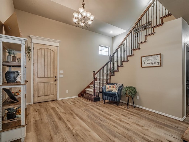 foyer entrance featuring a notable chandelier, light hardwood / wood-style floors, and a high ceiling