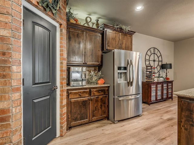 kitchen featuring stainless steel fridge with ice dispenser, light stone counters, and light wood-type flooring