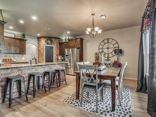 dining room with a chandelier, light wood-type flooring, and sink