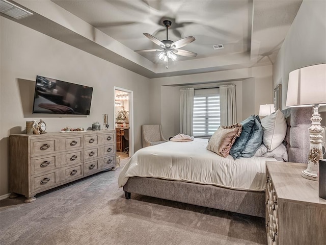 bedroom with carpet flooring, ensuite bathroom, ceiling fan, and a raised ceiling