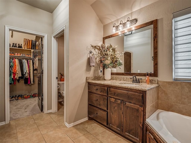 bathroom with toilet, vanity, tile patterned floors, and a tub