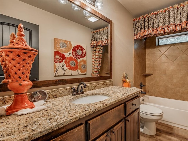 full bathroom with hardwood / wood-style floors, vanity, toilet, and tiled shower / bath combo