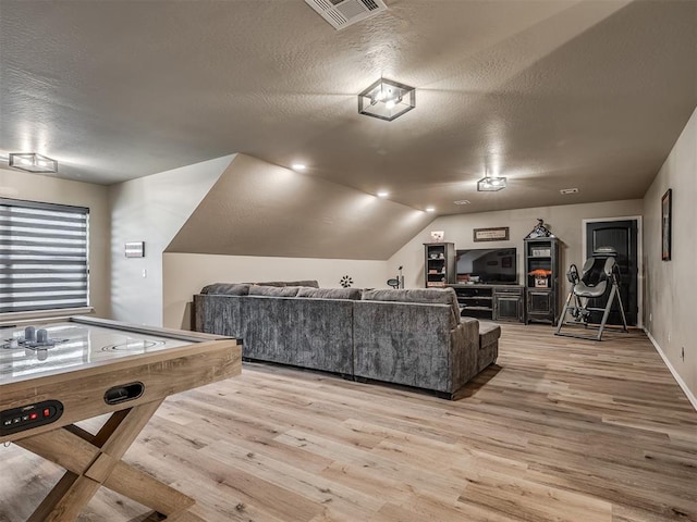 recreation room with a textured ceiling, light hardwood / wood-style floors, and vaulted ceiling