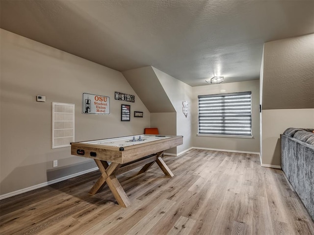 rec room with light hardwood / wood-style floors, lofted ceiling, and a textured ceiling