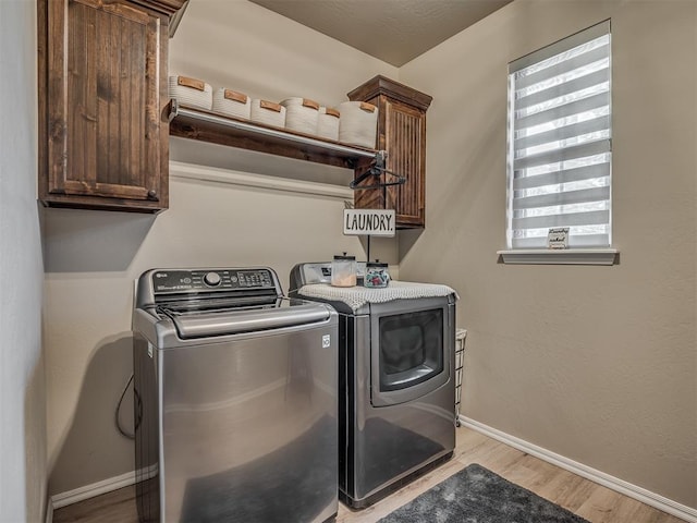 laundry room with washing machine and dryer, cabinets, and light hardwood / wood-style floors