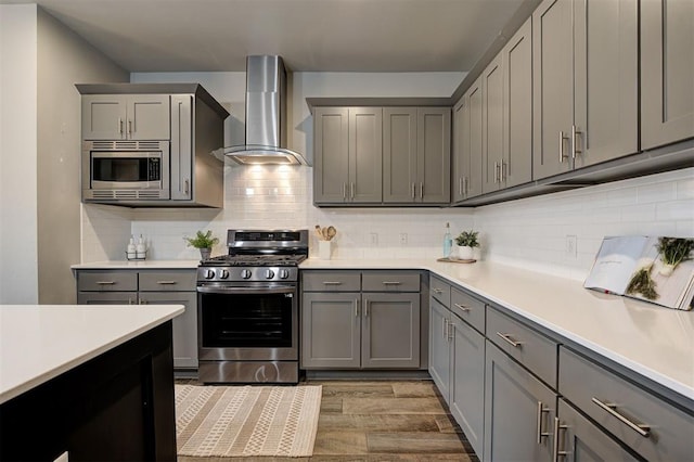 kitchen featuring wall chimney range hood, appliances with stainless steel finishes, and gray cabinets