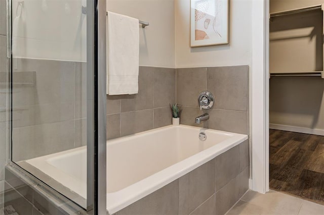 bathroom with tile patterned flooring and tiled tub