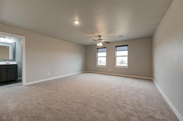 carpeted spare room featuring ceiling fan and sink