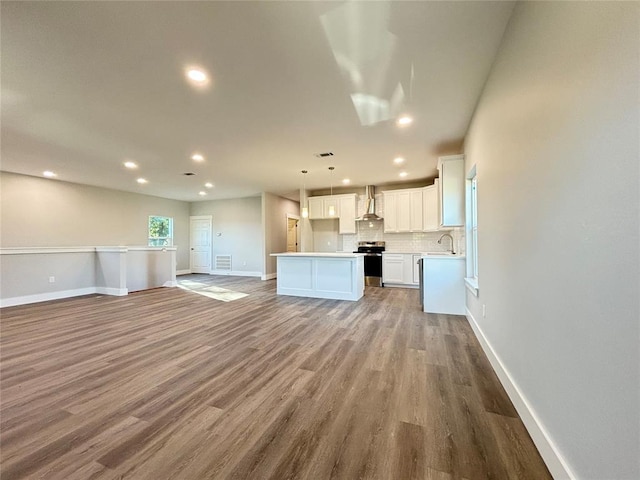 kitchen featuring pendant lighting, a center island, white cabinets, stainless steel electric stove, and light wood-type flooring