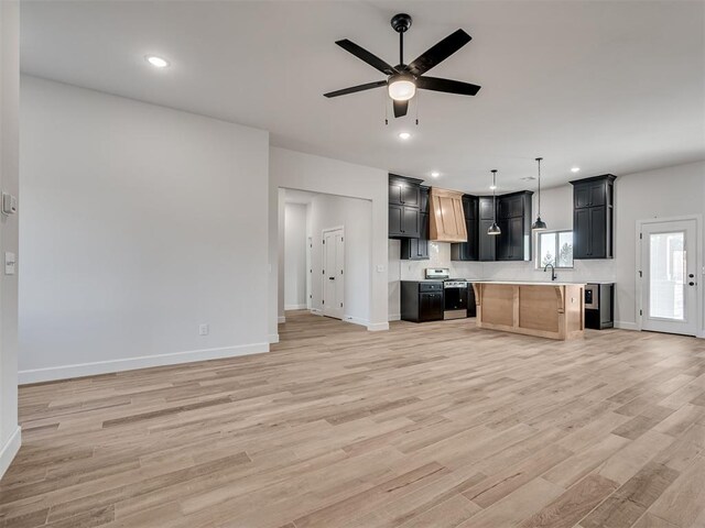 kitchen featuring a kitchen island, sink, stainless steel range, ceiling fan, and light wood-type flooring