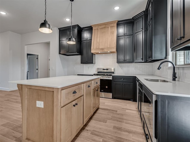 kitchen featuring a center island, decorative light fixtures, light brown cabinetry, and stainless steel gas range oven