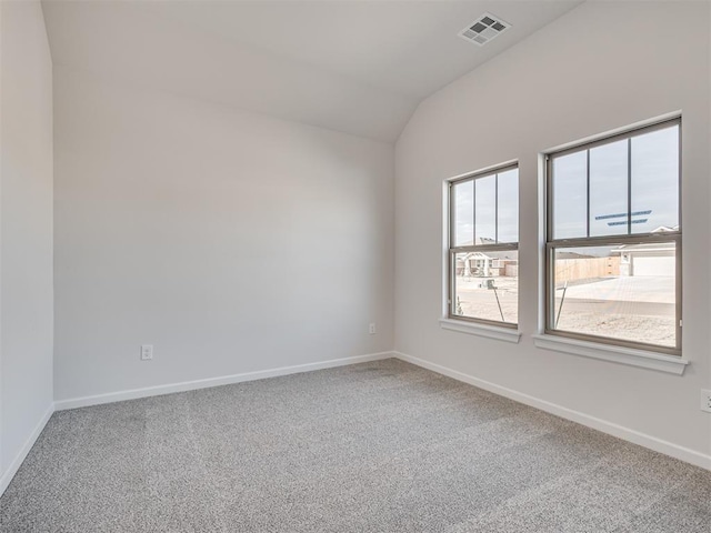 empty room featuring vaulted ceiling and carpet