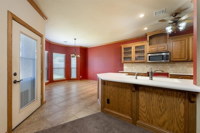 kitchen with pendant lighting, ceiling fan with notable chandelier, light tile patterned floors, and ornamental molding