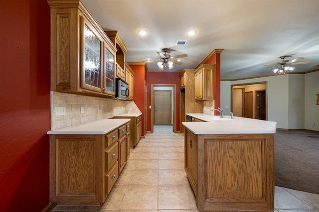 kitchen with ceiling fan, kitchen peninsula, crown molding, and tasteful backsplash