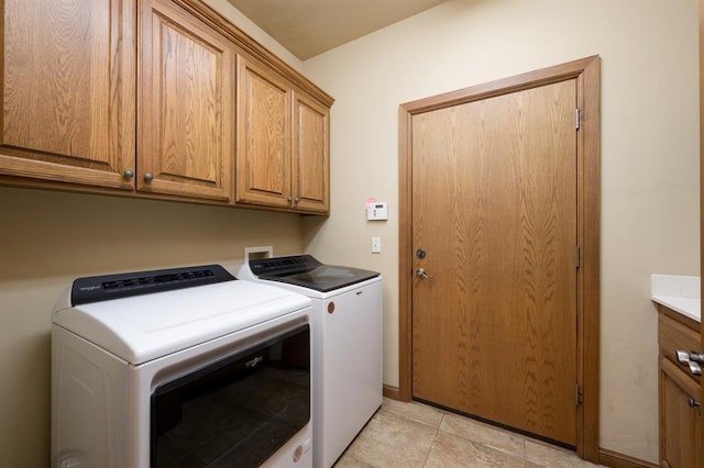 laundry area with cabinets, washing machine and dryer, and light tile patterned floors