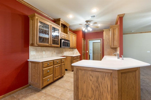 kitchen featuring kitchen peninsula, ceiling fan, crown molding, and sink