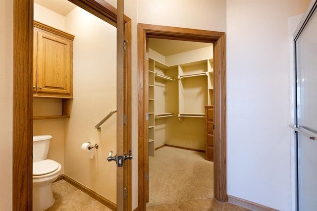 bathroom with tile patterned floors, toilet, and an enclosed shower