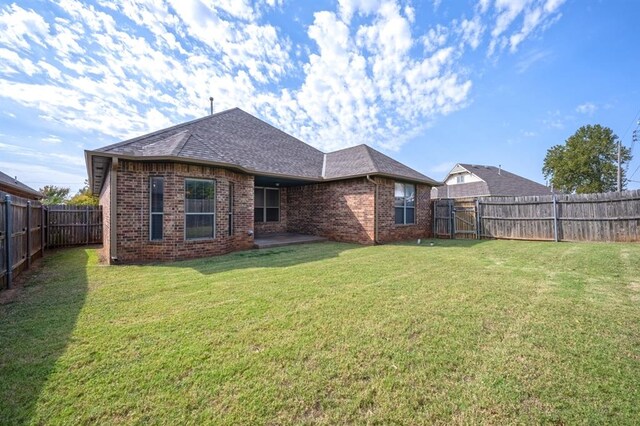 back of house with a patio and a lawn