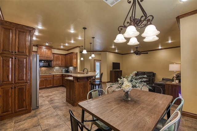 dining space featuring ceiling fan with notable chandelier, sink, and crown molding