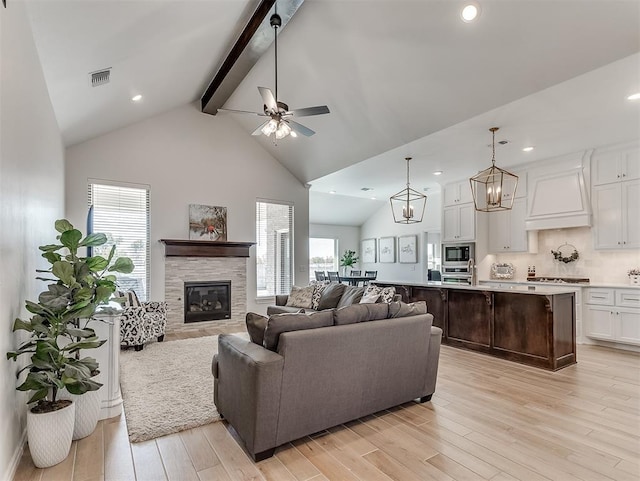 1718 Zayden Ln, Norman, OK 73072 - living room with beamed ceiling, light hardwood / wood-style floors, a stone fireplace, and ceiling fan